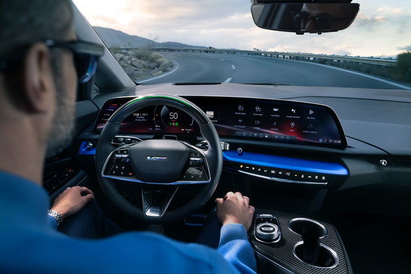 Front View of the 2026 OPTIQ-V Driving Through the Dusk Utilizing its Headlights | Cadillac of Marion in Marion IL